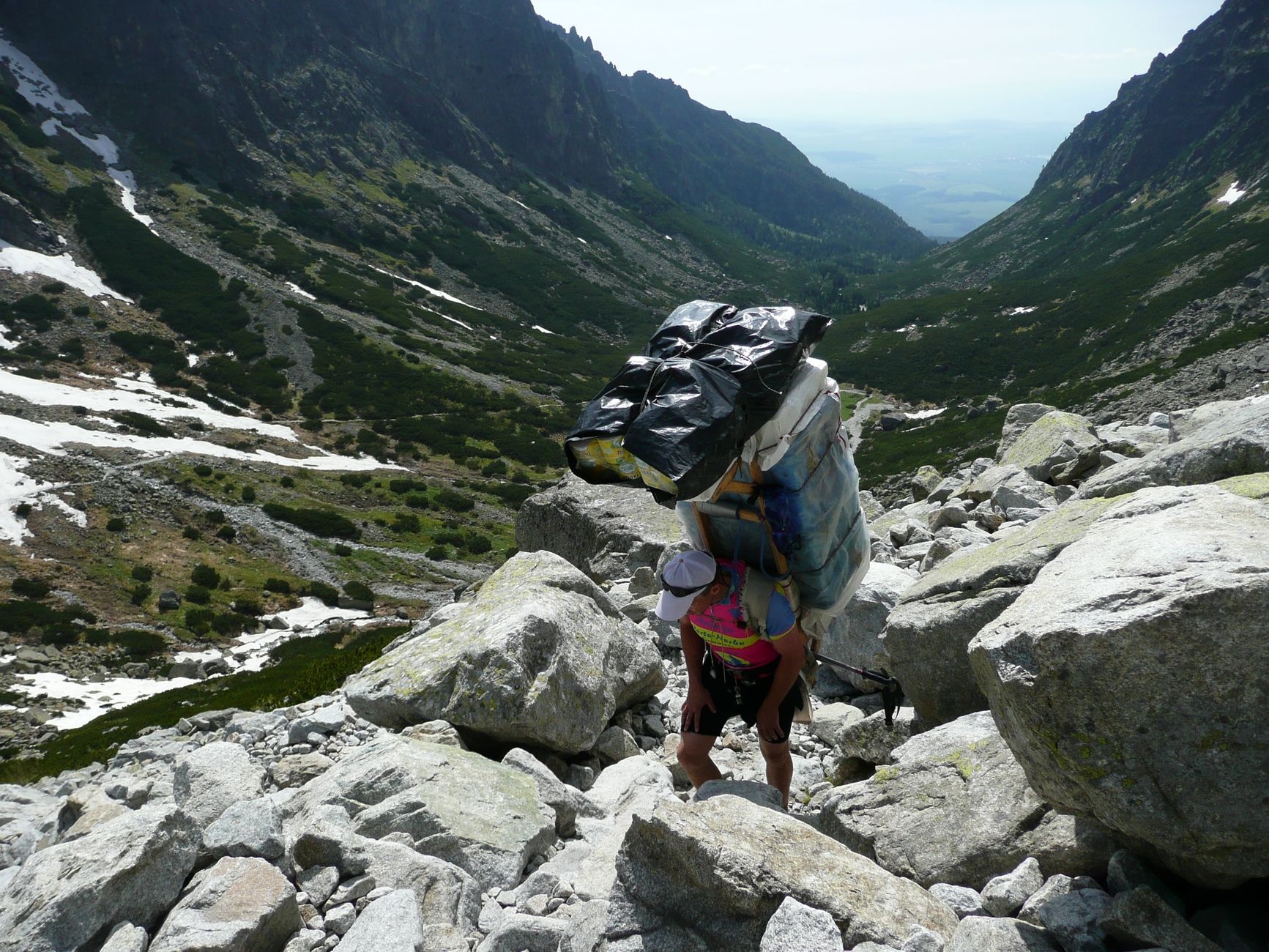 Man carrying large load while hiking through rugged mountain valley